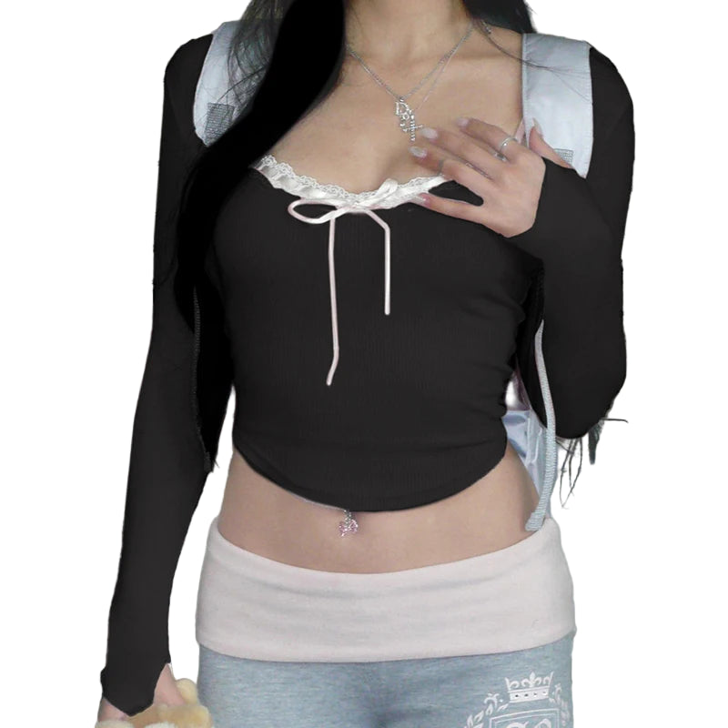 A person wearing a pink knit top with a square neckline and bow detail, paired with a high-waisted skirt.