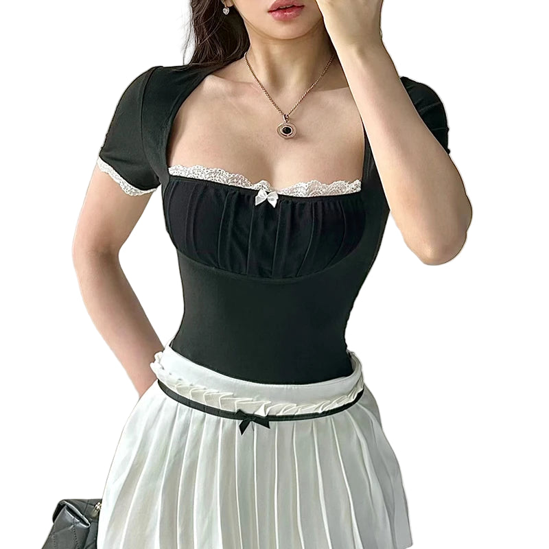 Woman wearing a black top with lace details and a white skirt against a neutral background