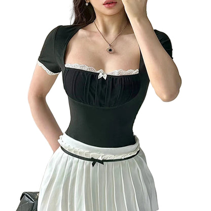 Woman wearing a black top with lace details and a white skirt against a neutral background