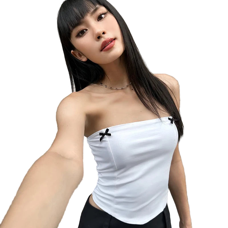 A woman wearing a white strapless tube top with black bow accents, paired with black pants.